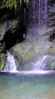 Şelale fıskiyeleri kaseye, kayalara, yosunlara, şelaleye, temiz kayalara, yosunlara çarpıyor. Saf şelale, temiz kaya, yosun görüntüleri. Sakin şelale, temiz kaya, doğada yosun..