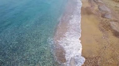 İnsansız hava aracı sahildeki dalgaların üzerinde süzülüyor, sörf hatlarını güzelleştiriyor. İHA 'dan görülen plaj dalgaları, sörf çizgileri. Kumsal boyunca sörf hattı, İHA 'lar tarafından ritmik olarak yakalanan dalgalar. Yüksek kalite 4k görüntü