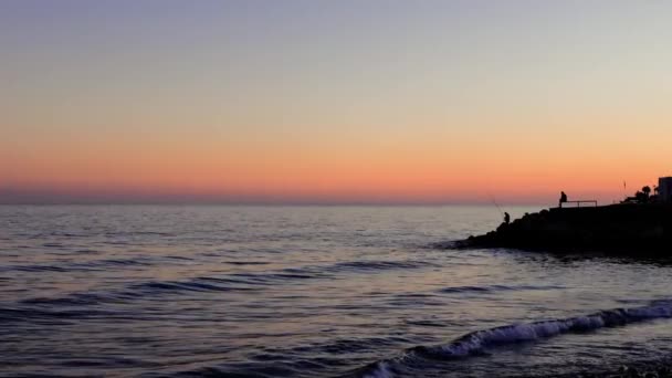 Σιλουέτα Του Ψαρά Στέκεται Απέναντι Στο Ηλιοβασίλεμα Κύματα Της Θάλασσας — Αρχείο Βίντεο