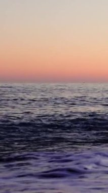 Gün batımında kumlu kumsalda dalgalar peş peşe geliyor. Her dalga sakin plaj akşamlarının özünü yakalıyor. Sahili saran ritmik dalgalarla gün batımı sahnesi. Yüksek kalite 4k görüntü