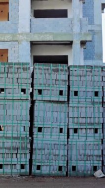 İnşaat alanındaki paletlere yığılmış bloklar. Kamera bina zeminine karşı geniş bir yığın gösteriyor. Blok yığını olan inşaat alanı, tamamlanmamış bina. Sünger taşı blokları yerinde.