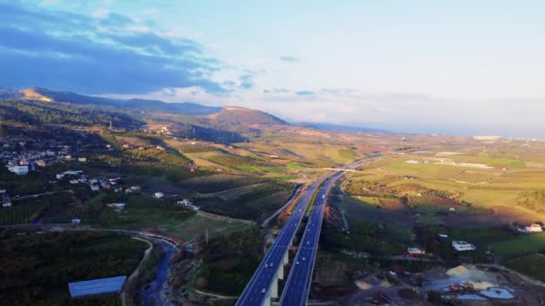 Drone Captura Tráfego Estrada Atravessando Campos Verdes Sob Céu Azul — Vídeo de Stock