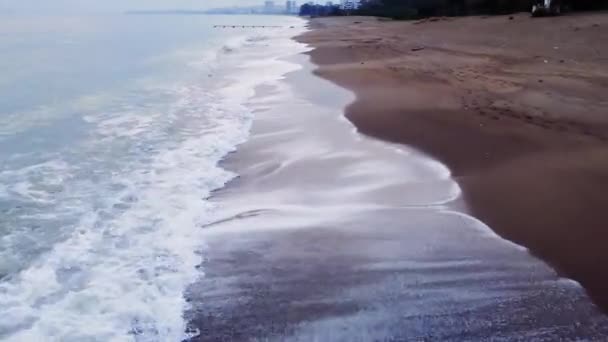 砂浜のサーフラインに沿った低ドローン飛行 沿岸線は地平線に広がり 海岸に対して波が打たれる この静かなシーンで海と海岸線のリズムパターンを探索する — ストック動画