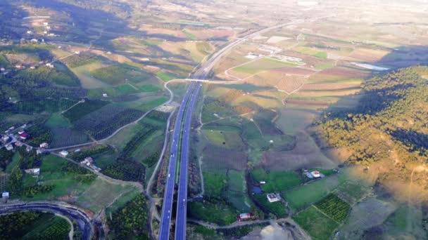 Drone Captura Tráfico Carretera Cruzando Campos Verdes Contra Cielo Azul — Vídeos de Stock