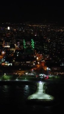 Mersin 'in panoramik drone görüntüsü, geceleri aydınlatılmış şehir manzarası. Hava görüntüleri aydınlatılmış şehir manzarasını çeker, Mersin 'in gece güzelliğini gözler önüne serer. Mersin 'de bir gece, aydınlatılmış şehir manzarasının insansız hava aracı videosu.