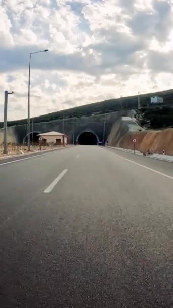 車は高速道路のトンネルに入り 暗闇が循環する道を示しています 車両の視点からトンネルへの車 トンネル入り口 ハイウェイの旅 車のハイライト トンネル体験を捉える — ストック動画