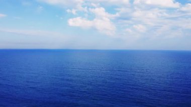 Gökyüzünde manzaralı beyaz bulutlarla derin mavi denizin üzerinde destansı bir uçuş. Deniz, gökyüzü, sonsuz ufukta bulut karışımı, sinematik sakin okyanus. Mükemmel sakin deniz, akşam gökyüzü bulutu sahne arkası deniz, gökyüzü, bulut.