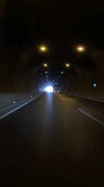 Araba tünelden çıkıyor, otoyolu gösteriyor. Arabadaki görüntüler tünel çıkışını gösteriyor, arabayı vurguluyor, tünel geçişini gösteriyor. Arabayı yakalar, tünelden otobana çıkar.