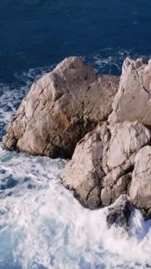 Kayalı sakin deniz, dalgalı okşamalar. Sakin, berrak mavi deniz, kaya merkezi, kırılan dalgalar nazik dokunuşlar. Her sahne kayayı yakalar, dalgaları uyum içinde kırar, doğanın güzelliğini gösterir..