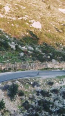 Drone dağ yolunda bisikletçiyi yakalıyor. Bisikletçiler için ideal, dağ yolu içerikli. Gösteriler bisikletçi, dağ yolculuğu. Bisikletçileri ve dağ yolu maceralarını keşfetmek için mükemmel..
