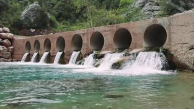 Büyüleyici bir köprü manzarası, canlı yeşil suları olan küçük bir nehrin üzerindeki baraj, dingin güzelliği aydınlatıyor. Görüntüler köprüyü, baraj entegrasyonunu gösteriyor. Yüksek kalite 4k görüntü