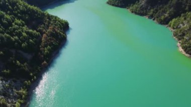 Dağ Gölü İHA 'sı görüntüleri, dik orman kıyılarını yakalıyor. Dağ gölü manzarası, el değmemiş doğal manzara. Mountain Lake Video 'sunda uzak güzellikler sergileniyor. Yüksek kalite 4k görüntü