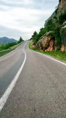 Dağlarda dolambaçlı yol boyunca giden birinci şahıs manzarası. Görüntü dar virajlı yolda yolculuğu yakalar. Kamera, manzaralı arazide dolambaçlı yolu takip ediyor. Yüksek kalite 4k görüntü