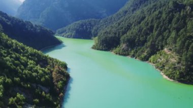 Zümrüt göl drone manzarası, dik orman kaplı kıyıları yakalıyor. Emerald Gölü 'nün videosu, el değmemiş doğa sahnesi. Zümrüt göl hava görüntüleri uzak güzellikleri gösteriyor. Yüksek kalite 4k görüntü