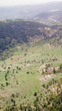 Hava manzarası, orman ortamındaki dağları, yemyeşil toprak yolu takip eder. İnsansız hava aracı görüntüleri manzarayı, kıvrımlı yolu olan dağları vurguluyor.