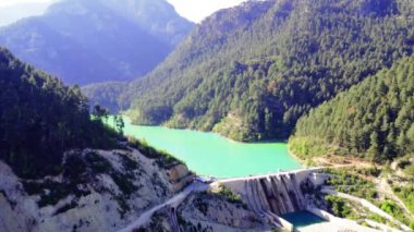 Dağ vadisindeki barajdan yenilenebilir enerji, insansız hava aracı manzarası. Yenilenebilir enerji, zümrüt göl ve ormanlık alan ele geçirildi. Yenilenebilir enerji sergilendi, baraj ve göl havası görüntüleri. Yüksek kalite 4k görüntü