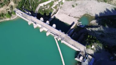 Dağ vadisinde su deposu, insansız hava aracı manzarası. Su deposu, ormanlık alanda zümrüt göl. Su deposu ve baraj hava görüntüleri, gözlerden uzak bir bölge. Yüksek kalite 4k görüntü