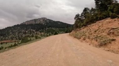 Dönek toprak bir yolu takip eden, resim gibi bir dağ ile huzurlu bir manzarada bir yolculuğa çıkın..