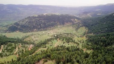 Hava perspektifi, yüksek dağların zeminine kurulmuş yemyeşil ağaçlarla dolu pitoresk bir vadiyi gözler önüne seriyor. Yüksek kalite 4k görüntü