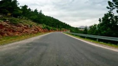Dağlarda manzaralı yolda giden birinci şahıs manzarası. Görüntüler arazide dönen manzaralı yolların altını çiziyor. Video, dar manzaralı yolda yolculuğu yakalıyor. Yüksek kalite 4k görüntü
