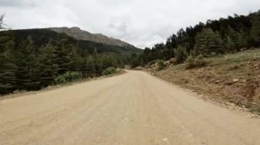 Dönek toprak yolu deneyimleyin. Yemyeşil ormanlarda, yüksek dağlarda, arka planda gezinirken..