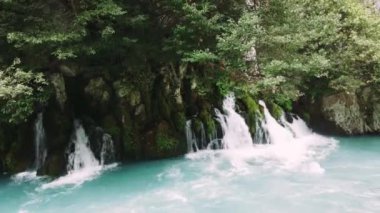 Küçük şelalelerin büyüsünün hızla akan turkuaz bir nehre aktığını hissedin. Yüksek kalite 4k görüntü