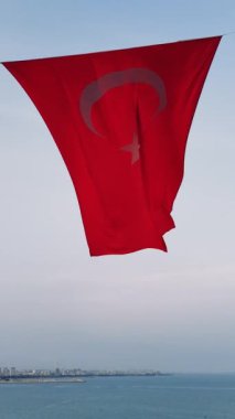 Hilal şeklinde parlak kırmızı bir Türkiye bayrağı ve deniz koyunun pitoresk zeminine güzel bir şekilde dalgalanan bir yıldız. Yüksek kalite 4k görüntü