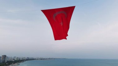 Hilal şeklinde parlak kırmızı bir Türkiye bayrağı ve deniz koyunun pitoresk zeminine güzel bir şekilde dalgalanan bir yıldız. Yüksek kalite 4k görüntü