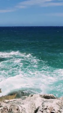 Serenitys Edge: Turkuaz Denizi 'nin bir bakışı, türkuaz dalgaların kayalıklara çarpmasıyla okyanusun ham gücünü ve güzelliğini deneyimlemektedir. Yüksek kalite 4k görüntü