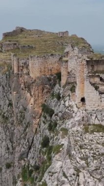 Türkiye 'nin Adana kentindeki bir dağın tepesine kurulmuş tarihi bir kale olan Anavarza Kalesi' nin çarpıcı görüntülerini kaydeden bir dron görülüyor. Karmaşık mimariyi keşfedin ve antik mühendislik becerilerine hayret edin.. 