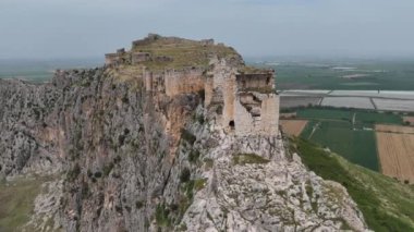 Türkiye 'nin Adana kentindeki bir dağın tepesine kurulmuş tarihi bir kale olan Anavarza Kalesi' nin çarpıcı görüntülerini kaydeden bir dron görülüyor. Karmaşık mimariyi keşfedin ve antik mühendislik becerilerine hayret edin.. 