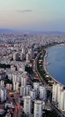 Güneş batarken Mersin, Türkiye 'nin büyüleyici insansız hava aracı görüntüsü. Canlı şehir manzarası sahnenin üzerine büyülü bir ışık saçan batan güneşin sıcak parıltısıyla kıyı şeridi boyunca uzanır..