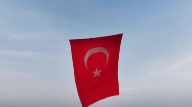 Hilal ay ve yıldızla süslenmiş canlı bir Türk bayrağı rüzgarda zarif bir şekilde dans ediyor..