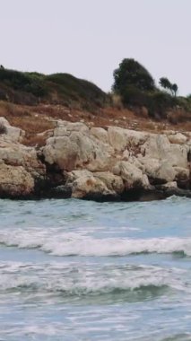 Dalgaların sakin bir sahili kayalık bir kıyıya doğru yavaşça yuvarlanırken, bir Akdeniz adasının huzurlu güzelliğini gözler önüne seriyor..