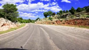 Nefes kesici bir dağ manzarasında nefes kesici bir yolculuğa çıkın. Pürüzsüz asfalt rüzgarları yemyeşil yeşil gökyüzünün altında dağınık beyaz bulutlar altında