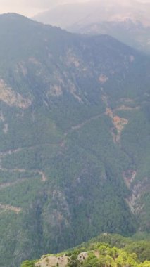 Orman dağlarının üzerinden uçan dronun panoramik görüntüsü. İnsansız hava aracı yemyeşil ve yüksek zirveleriyle nefes kesici manzaralar yakalar. Huzurlu ve görkemli manzara görüntüsü arayanlar için mükemmel.. 