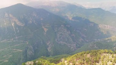 Orman dağlarının üzerinden uçan dronun panoramik görüntüsü. İnsansız hava aracı yemyeşil ve yüksek zirveleriyle nefes kesici manzaralar yakalar. Huzurlu ve görkemli manzara görüntüsü arayanlar için mükemmel.. 