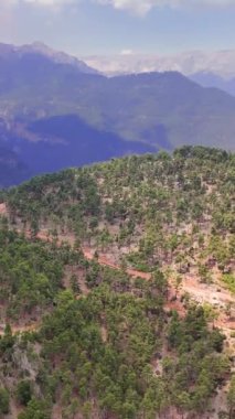 Orman dağlarının üzerinden uçan dronun panoramik görüntüsü dağ arazisinin engin genişliğini yakalar. Görülen her dağ zirvesi ile yukarıdan gelen güzelliğe ve ihtişamlı dağ manzaralarına tanık olun..