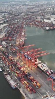 Drone, konteynır gemileriyle vinç operasyonlarını vurgulayarak gün batımında limanı filme alıyor. Vinç, liman ve konteyner gemisi arasındaki konteynırları hareket ettiriyor.. 