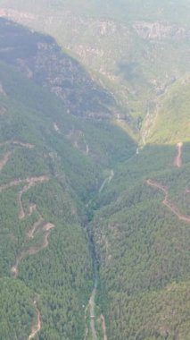 Yeşil bir vadide engebeli tepelerle çevrili eğimli bir dağ yolunun manzaralı manzarası. Seyahat, doğa ve macera temaları için ideal