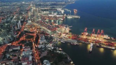 İnsansız hava aracı gece limanında aydınlık liman tesislerini vurguluyor. Port vinçleri yükleme ve boşaltma sahneleri gece gökyüzü altında hareketli liman faaliyetlerini etkin çalışan vinçlerle yakalıyor..