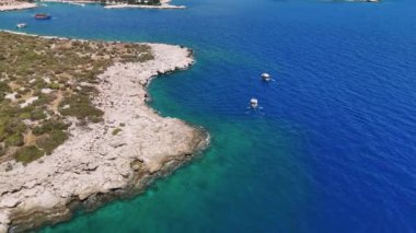 Canlı yeşil yapraklar ve ışıl ışıl turkuaz sularla bezenmiş çarpıcı bir kıyı şeridine doğru iki tekne süzülüyor. Sahne huzurlu ve resimli bir kıyı manzarası yakalıyor.