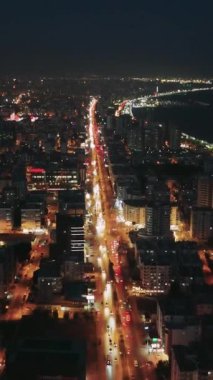 Kıyı kenti, karanlık Akdeniz 'e bitişik parıldayan binalar ve hareketli caddelere sahiptir. Arabalar kıyı yolu boyunca yol alırlar.