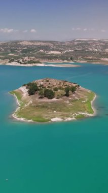 Havadan bakıldığında turkuaz bir göle yerleşmiş küçük bir ada görülüyor. Kamera daha yakına süzülüyor, bereketli manzaranın ve huzurlu suların karmaşık detaylarını ortaya çıkarıyor.