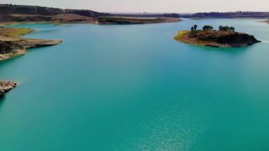Havadan bakıldığında, resim adaları ve canlı yeşillikler tarafından kucaklanan sakin bir turkuaz göl sergileniyor. Doğa ve seyahat temalarını vurgulayan görseller için ideal