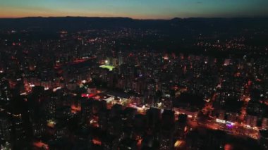 Kuşbakışı görüş, alacakaranlığa yenik düşen bir şehri yavaş yavaş yakalıyor. Güneş ufuktan batarken. Sokak lambaları ve bina ışıkları şehir manzarasını aydınlatıyor