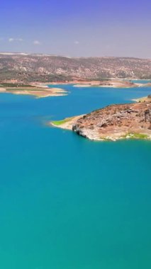 Hava manzaraları, engebeli uçurumlar ve geniş açık gökyüzünün yer aldığı sakin mavi bir kıyı şeridini yakalıyor, çarpıcı doğal güzellik ve barışçıl bir manzara sunuyor.