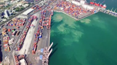 Turnalar nakliye konteynırlarını hareketli bir limanda büyük gemilerden yükleyip boşaltırlar. Sahne deniz lojistiğinin dinamik aktivitesini yakalıyor.