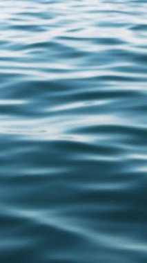 Üzerinde hafif dalgalar hareket eden bir su kütlesinin yüzeyi. Su koyu mavi bir renktir ve gökyüzü yüzeyine yansımaktadır.