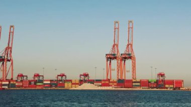 Konteynır vinçleri hareketli bir limanda etkili bir şekilde kargo konteynırlarını yükleyip taşıyarak denizcilik lojistik ve küresel ticaret faaliyetlerinin dinamik operasyonlarını gözler önüne seriyor